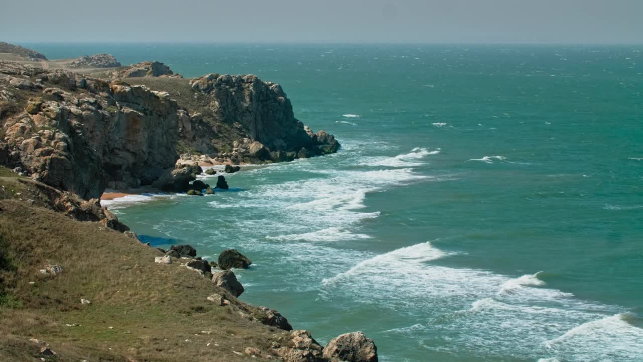 海浪拍打在岩石高原上，把一个绿色的大泻湖分割开来。克里米亚,将军的海滩。用三脚架拍摄的长镜头视频素材