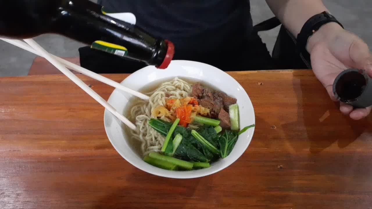 在一碗鸡肉面中加入瓶装酱油视频素材