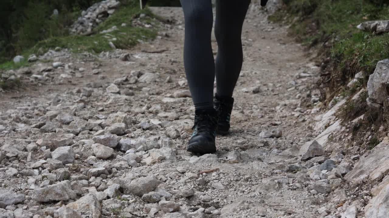 特写:皮革登山鞋和女人爬陡峭的山的细节视频素材