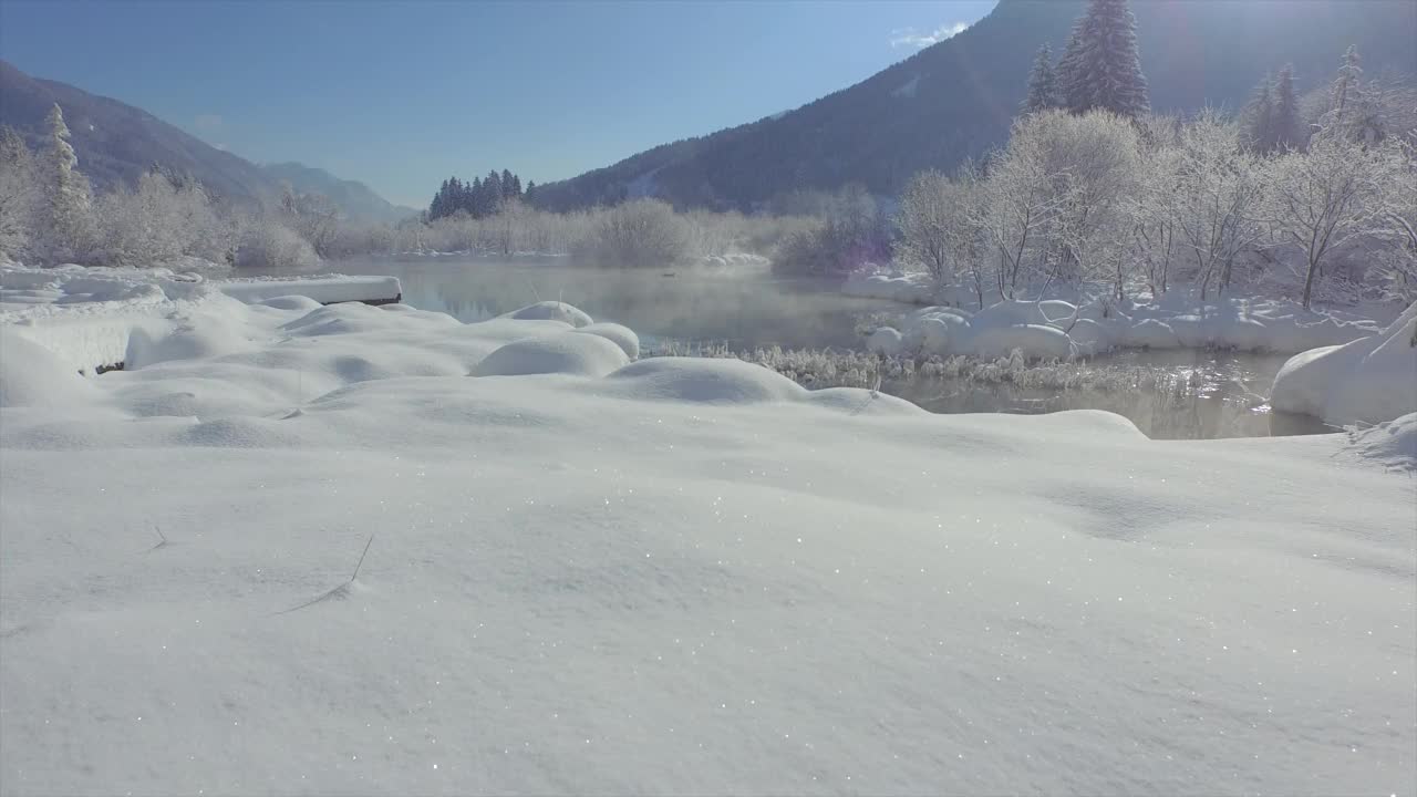 航拍:低空飞行在高高的积雪和泽伦奇水晶绿色的泉水之上视频素材