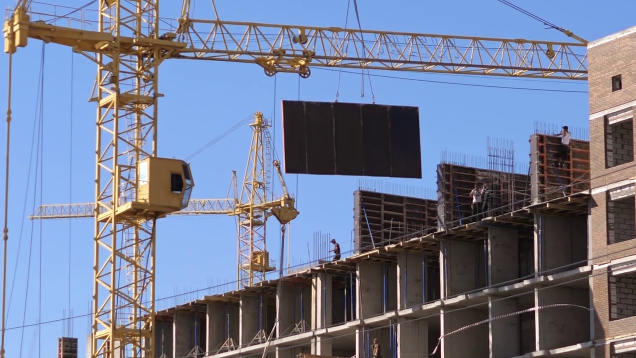 一个大型建筑工地，有许多高层起重机在建筑物上工作。在晴朗的天空背景下，新塔的建造正在进行中视频素材