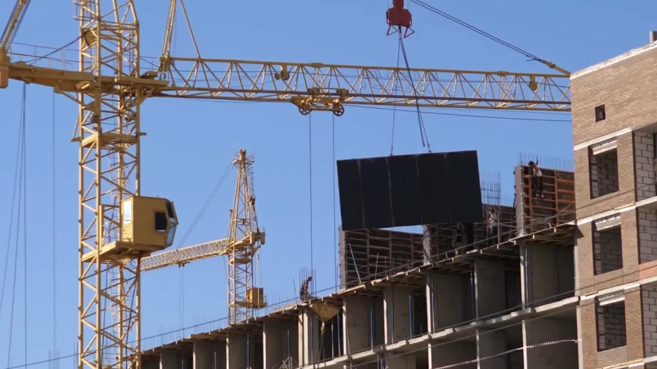 一个大型建筑工地，有许多高层起重机在建筑物上工作。在晴朗的天空背景下，新塔的建造正在进行中视频素材