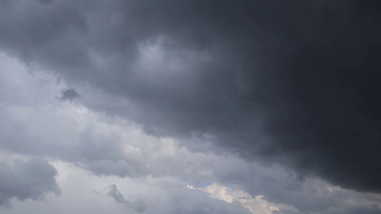 黑暗的暴风雨云在天空中慢慢飘过。这是一个阴沉的日子，灰色的雨云漂浮在黑暗的天空，预示着要下雨。阴雨天气中神奇的戏剧性天空视频下载