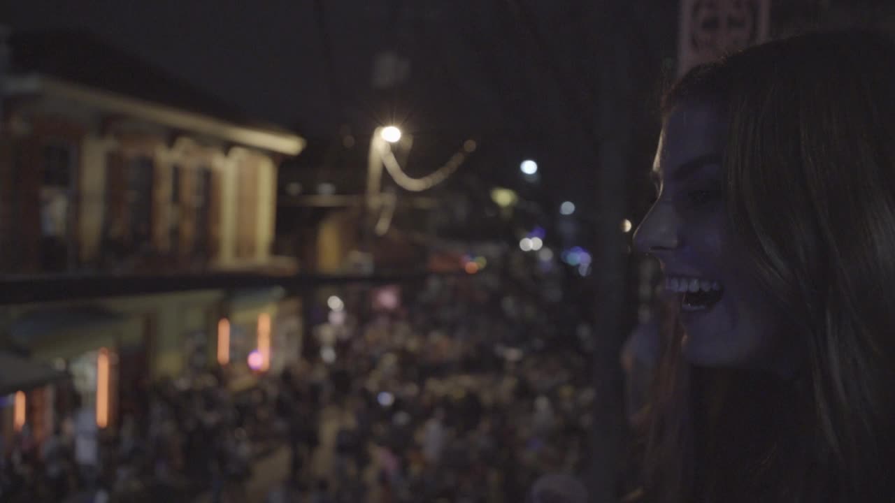 手握近角度笑女人在阳台上可以是波旁街在狂欢节期间。一群人走在街上视频素材