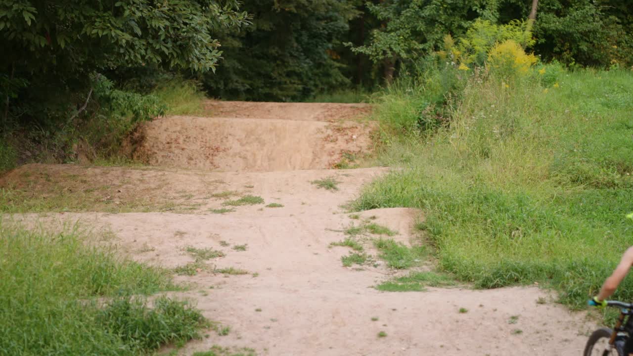 山地自行车运动和赛车，男子骑着MTB自行车在森林的土路上，后视图慢动作视频素材