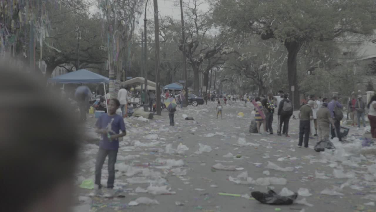 手持中等角度的家庭走在什么可能是拥挤的波旁街或法国区在新奥尔良的狂欢节游行。街道上到处都是垃圾视频素材