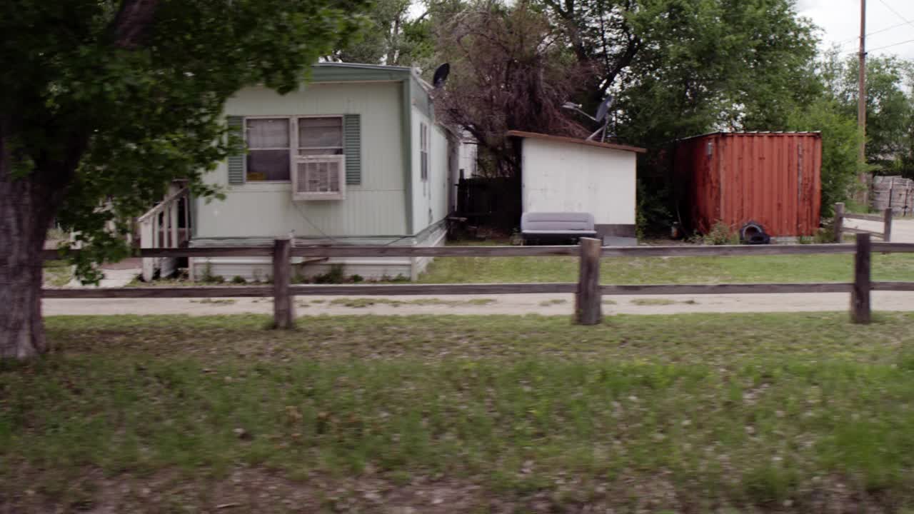 慢行或慢行的过程，沿着有房屋和拖车的乡村道路直走在乡村地区的右侧。树码。阴视频素材