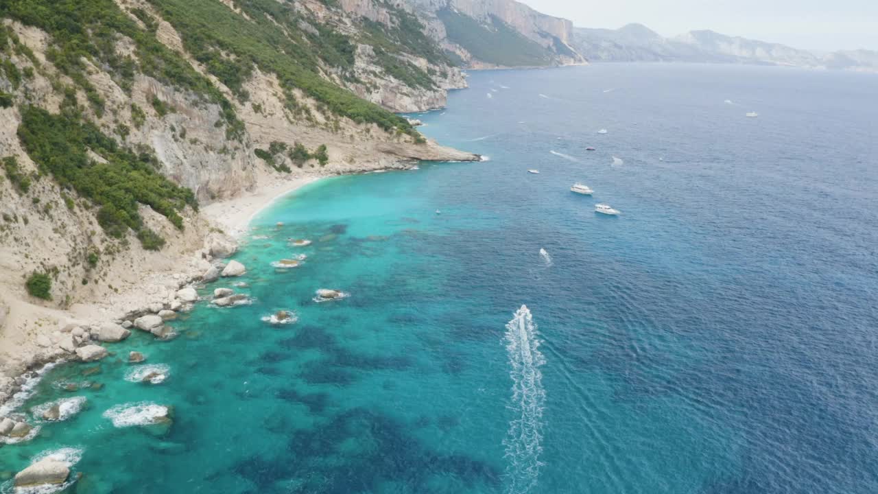 夏天美丽的海景有山，碧蓝翠绿的海水清澈，小船和游艇。飞越海岸线的空中飞行。意大利撒丁岛视频下载