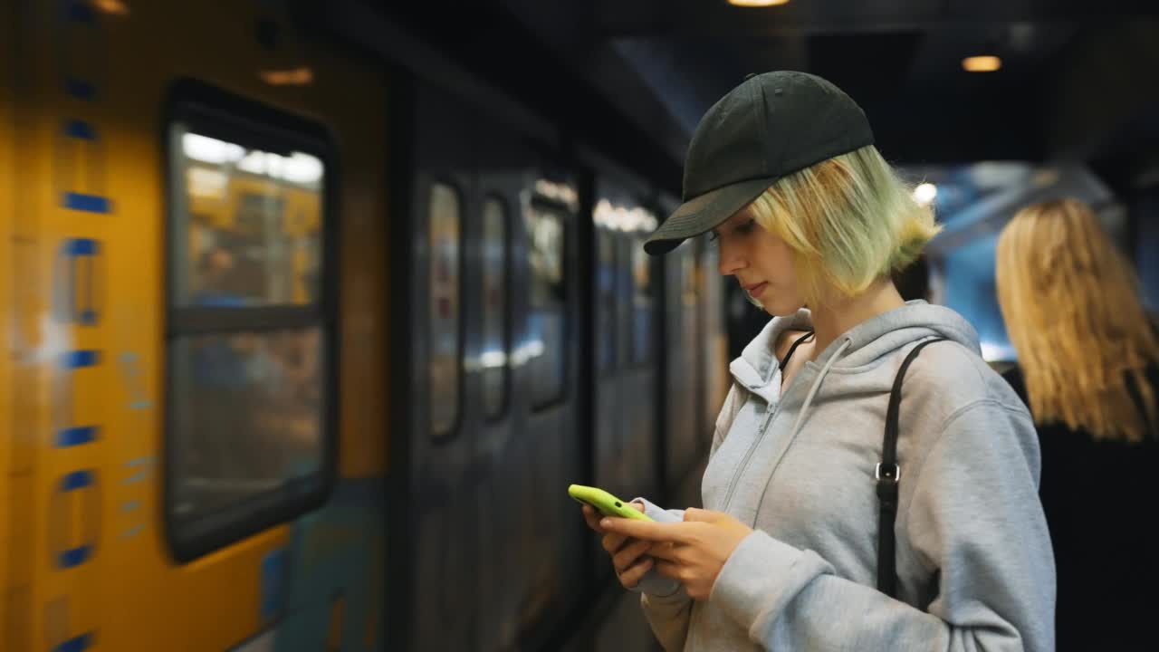 手持智能手机的少女在地铁里等车。视频素材