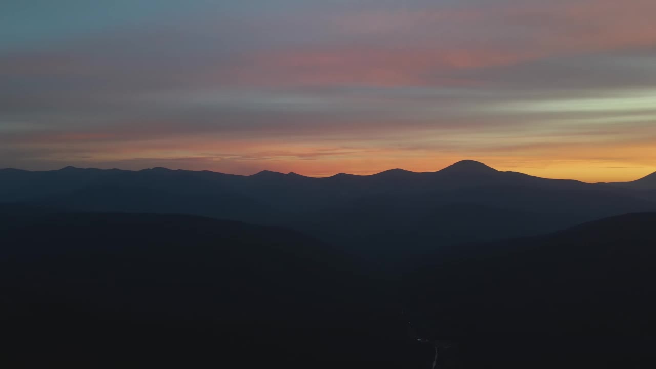 鸟瞰图，黑暗的小山与明亮的阳光夕阳在日落。黄昏时分，山峰朦胧，山谷朦胧视频素材