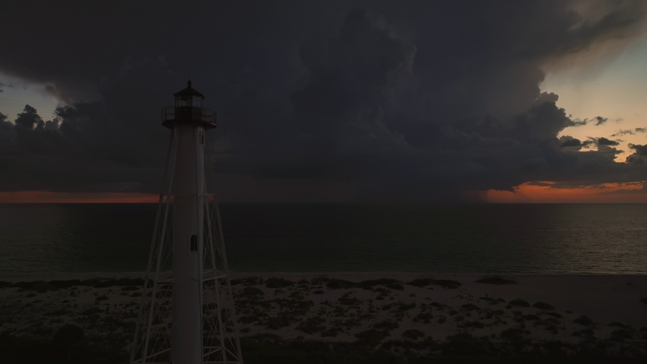 海岸上的白色灯塔，在暴风雨的夜晚闪烁着灯光，供商业船只航行。海面上有雷暴和闪电，对船只构成危险视频素材