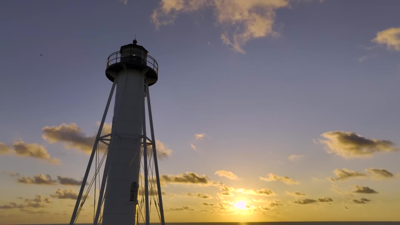 白色的灯塔矗立在海边，映衬着黄色的夕阳天空，供商业船只航行视频素材