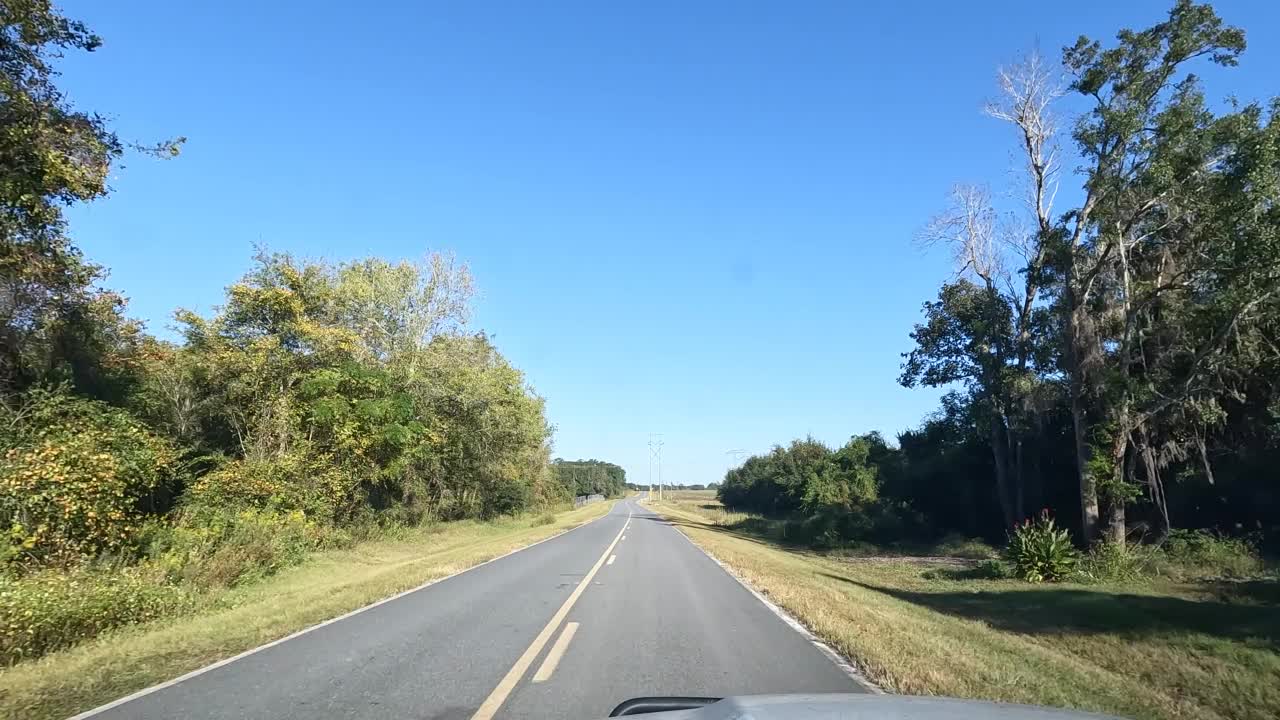 手持司机的观点，而旅行的弯曲沥青道路之间的农田与HT电力线视频素材