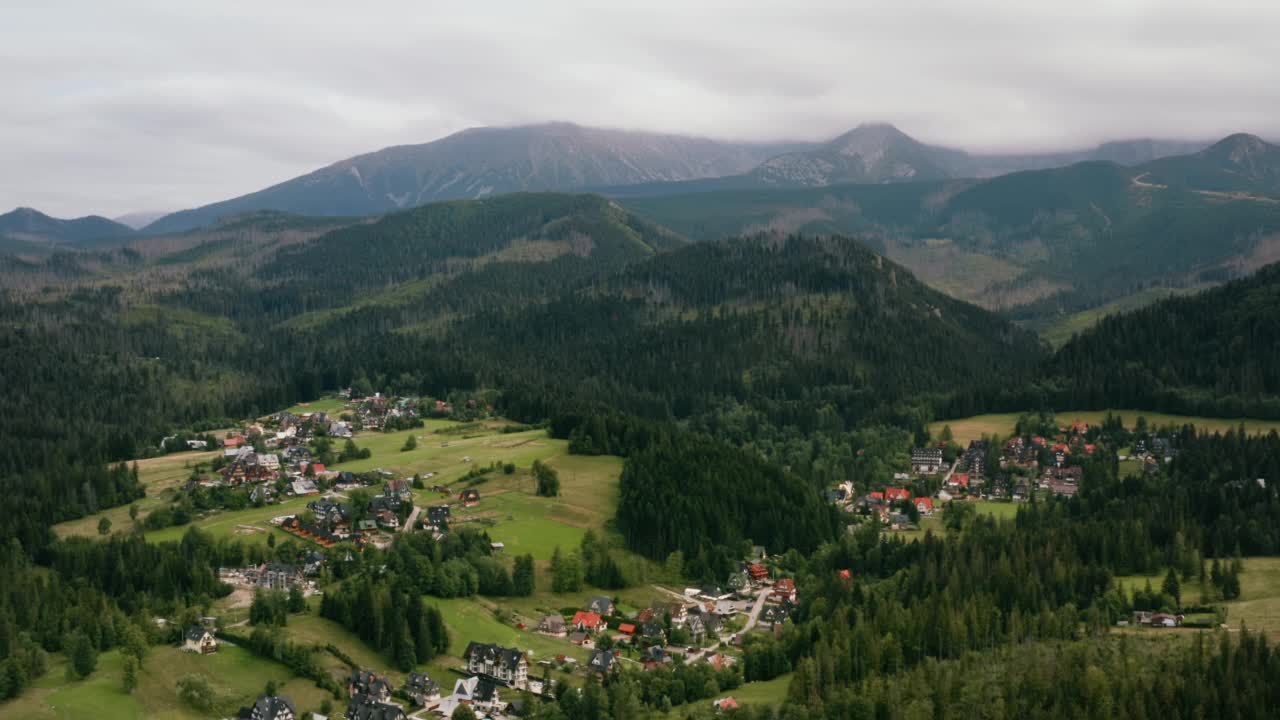 空中山村风景如画。无人机拍摄高山自然景观。绿色的松树森林，乡村，小屋和山上的旅馆。塔拉山被雨云覆盖。扎科帕内、波兰视频素材