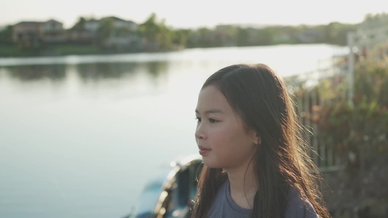 学龄前混合亚洲女孩在户外湖边微笑，健康和快乐的儿童肖像，积极的心理健康和幸福的概念视频素材