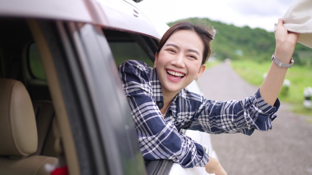 4K年轻的亚洲女子坐在车里享受夏季旅游假期的公路旅行。视频素材