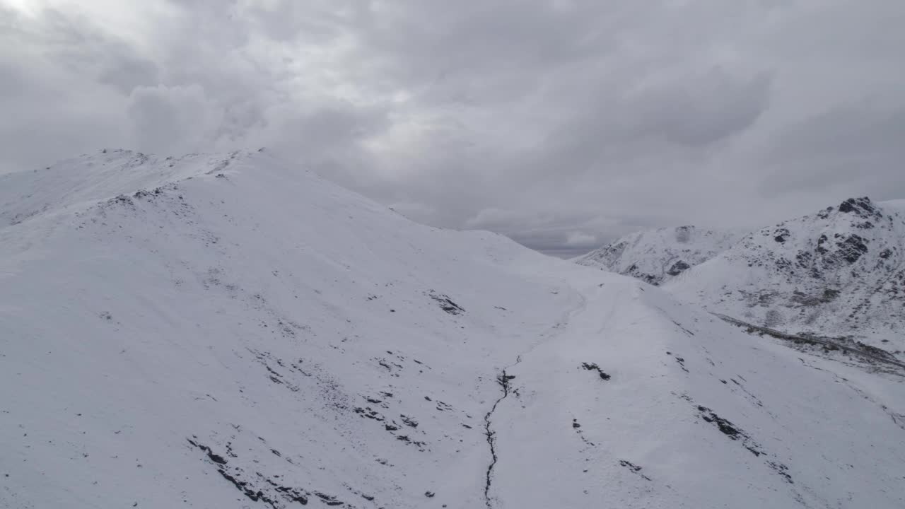 无人机拍摄的阿拉斯加哈奇尔山口美景，多云天空下积雪覆盖的山口视频素材