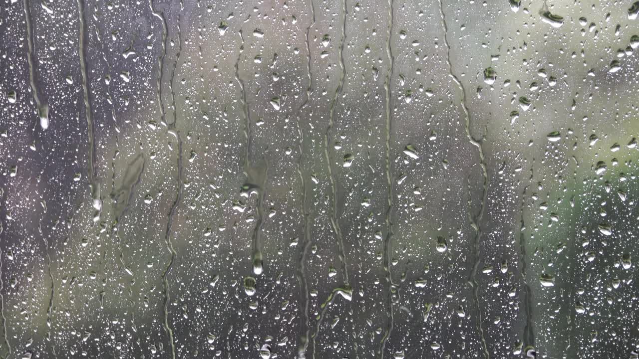 雨天的天气在湿窗的玻璃后面，倾盆大雨落下。视频素材