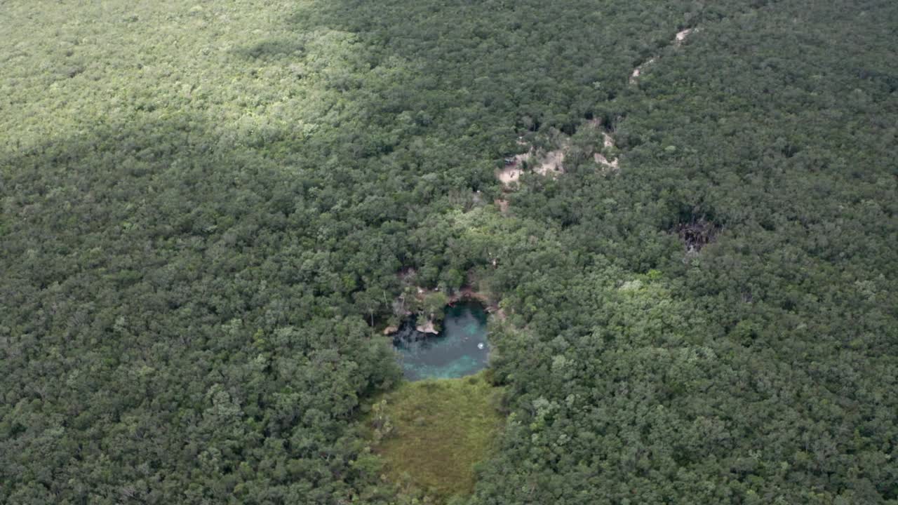 航拍的绿色森林景观与一个小的蓝色湖泊在农村地区在白天视频素材