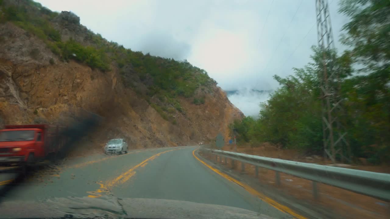 透过汽车的挡风玻璃看到的道路山和阴天。视频素材