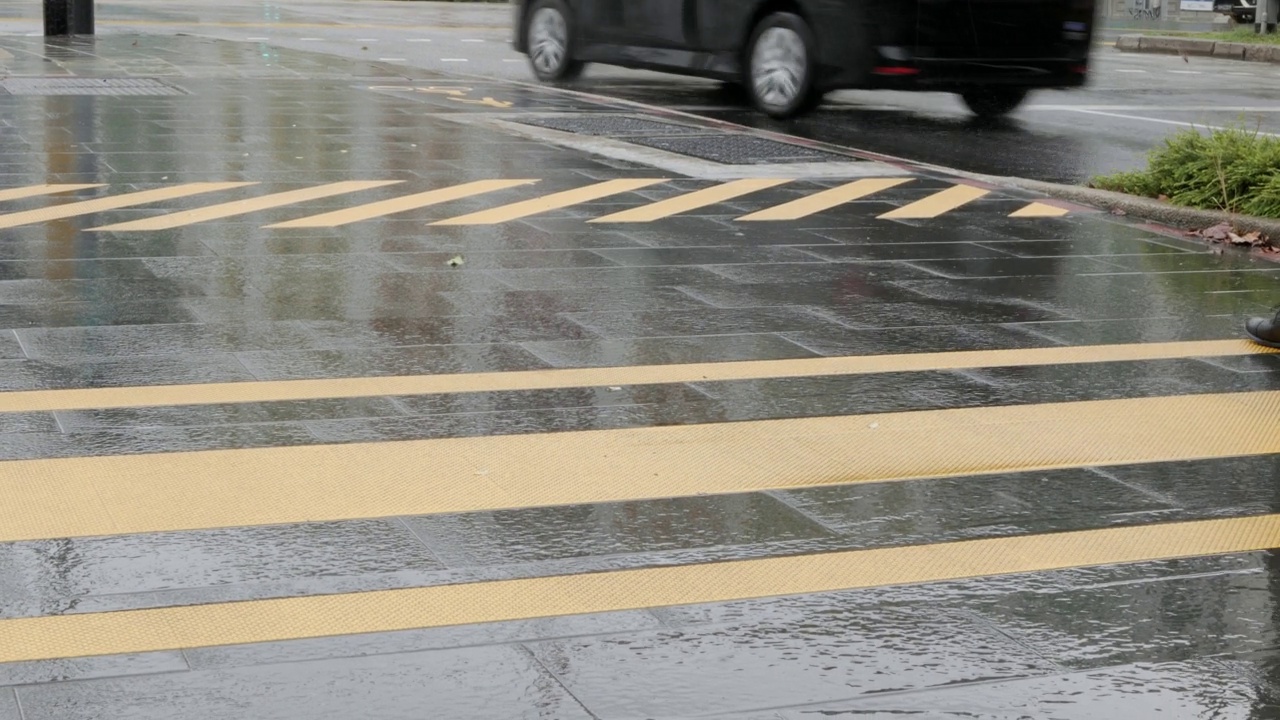 滂沱大雨在城市交叉线道路白天与行人交叉走的道路。有选择地聚焦在沥青路上的雨滴。视频素材