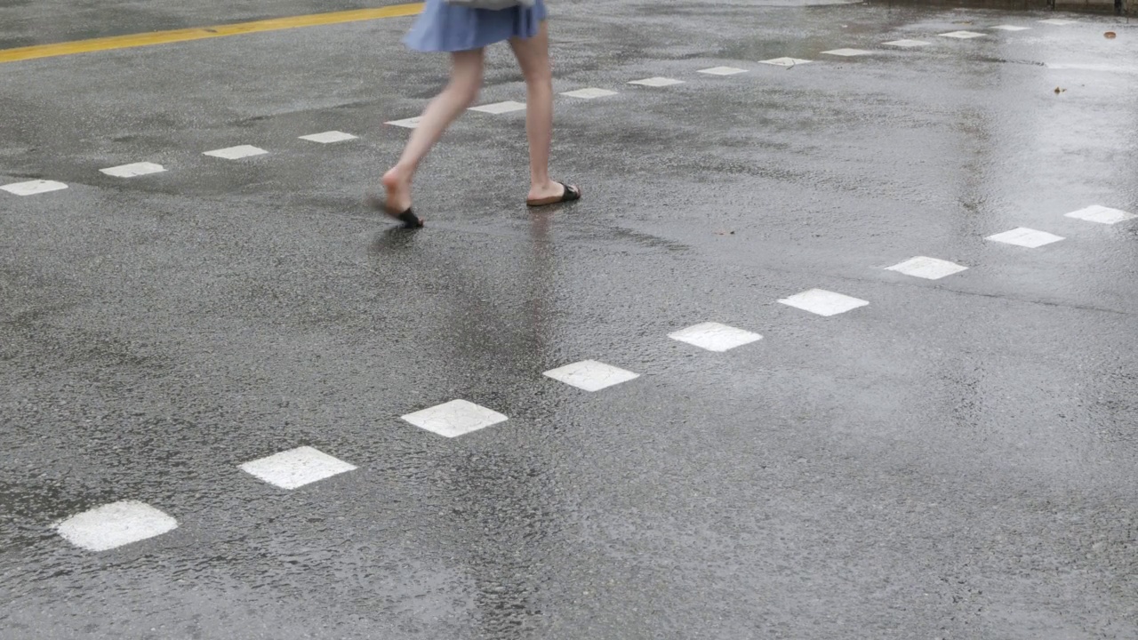 滂沱大雨在城市交叉线道路白天与行人交叉走的道路。有选择地聚焦在沥青路上的雨滴。视频素材