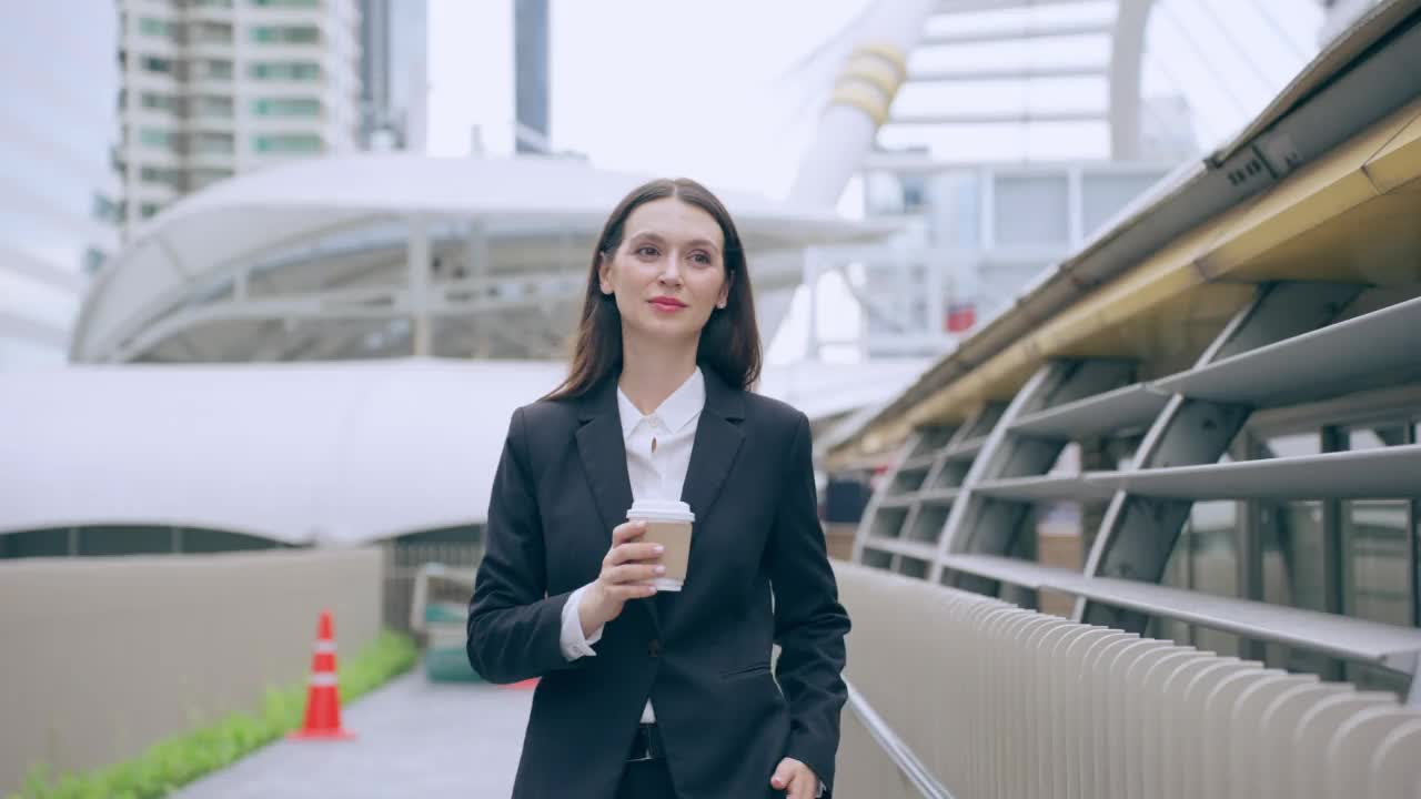 白种女商人拿着咖啡走在城市的户外。迷人美丽的女职员工人人们感到快乐和自信的同时花时间走到办公室的公司。视频素材