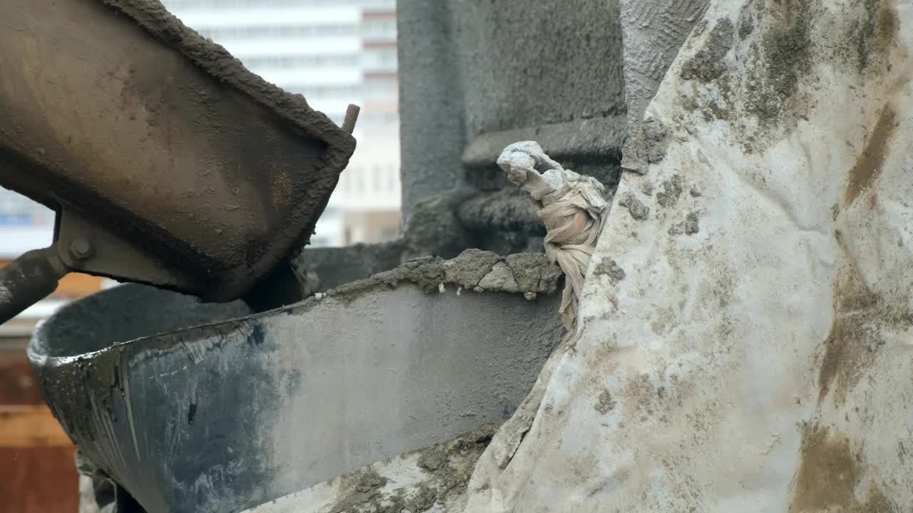 在施工现场，混凝土从混凝土搅拌机中倒入容器中。视频素材