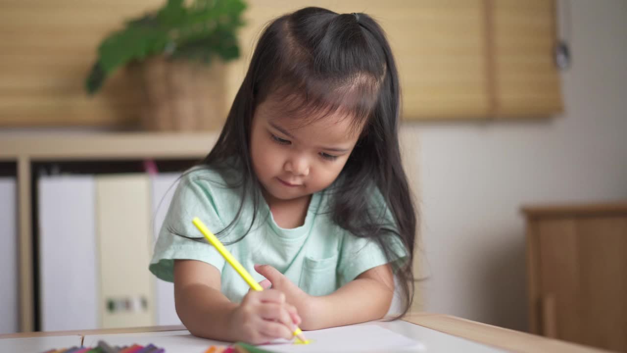 浓缩亚洲小女孩在家里客厅的纸上涂色视频素材