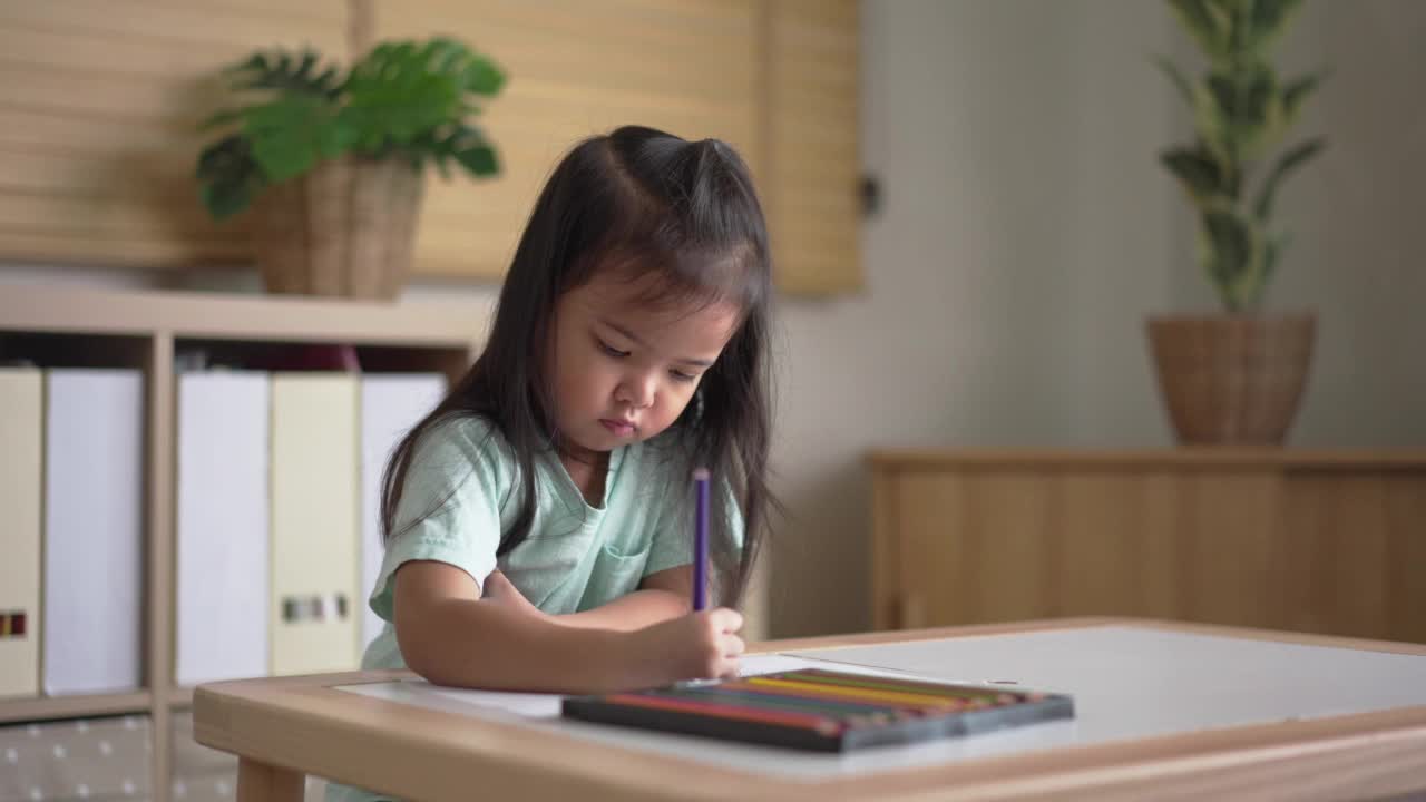 浓缩亚洲小女孩在家里客厅的纸上涂色视频素材