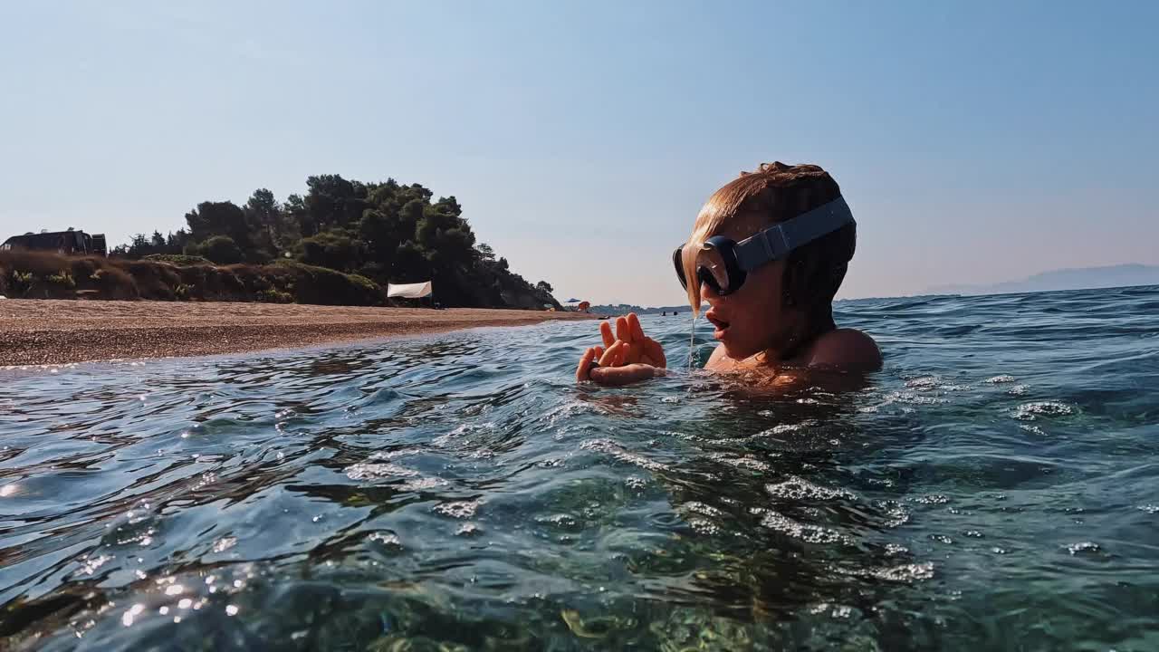 好奇的金发小孩捡起水下的鹅卵石视频素材