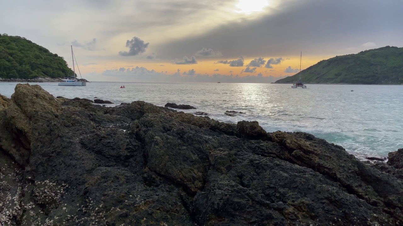 双体船在夕阳下航行在泰国普吉岛的岩石湾视频素材