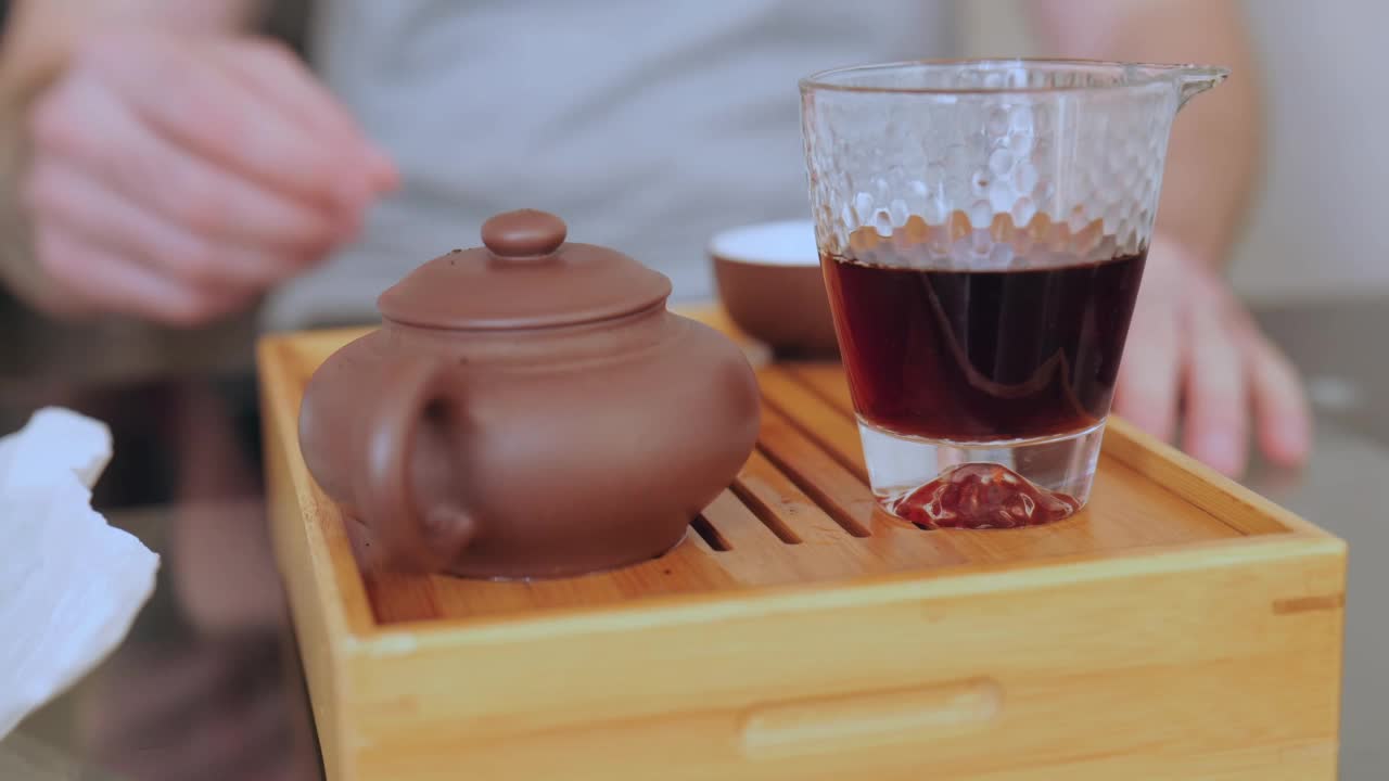 在传统的中国茶道中，一名男子的手将茶从茶海中倒入碗中。倒普洱茶的男人。4 k。慢动作视频素材