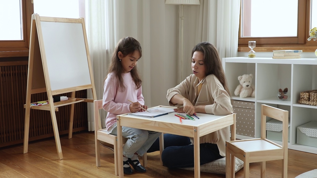 快乐的年轻妈妈和可爱的女儿在一起聊天，画画视频素材