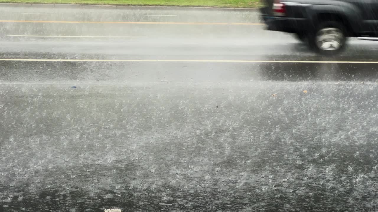 慢动作镜头，大雨水滴在沥青上的大水坑里，淹没了街道。视频素材