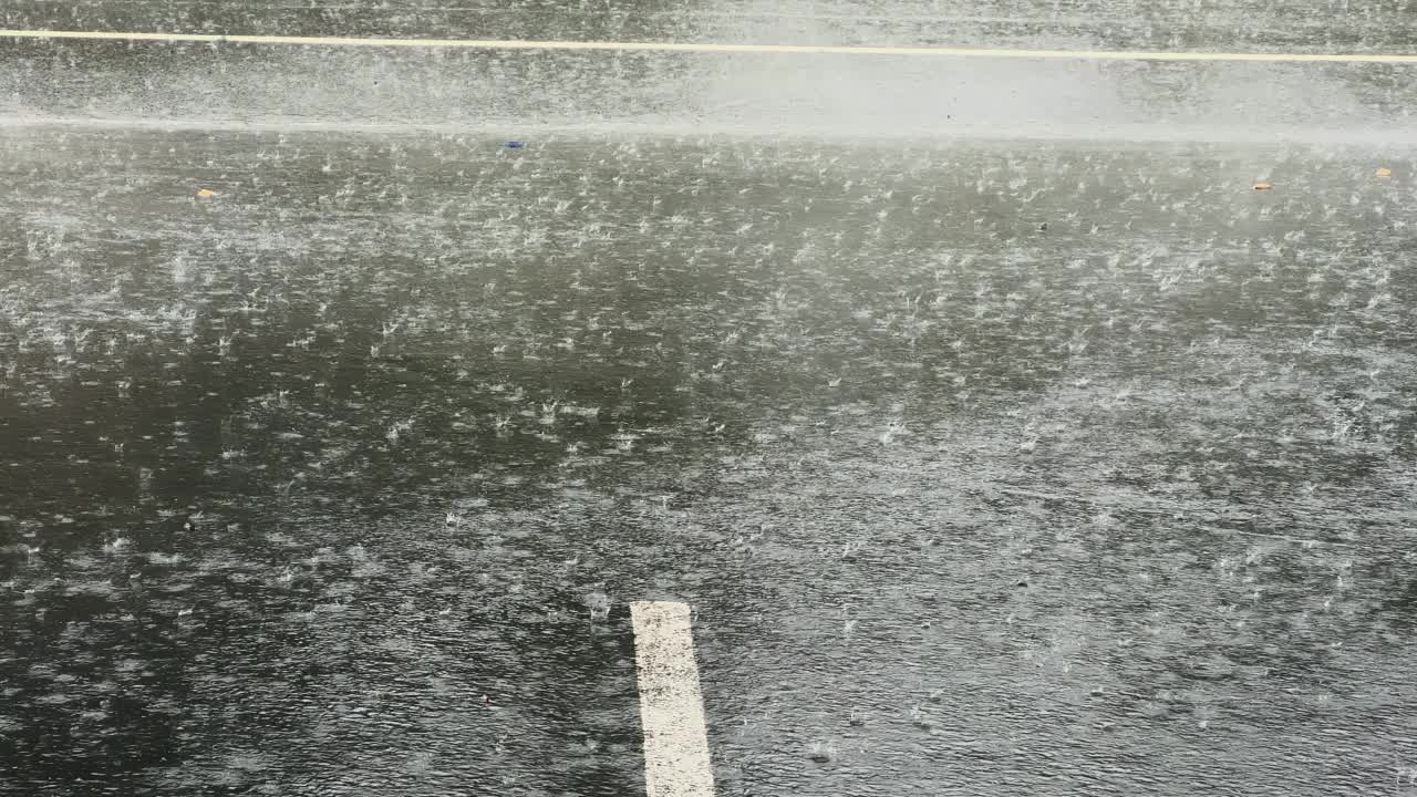 慢动作，大雨水滴在沥青上的大水坑里，淹没了街道。视频素材