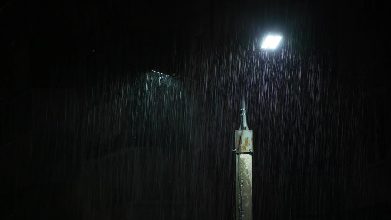 夜间大雨下的双led灯柱。中等尺寸的雨滴对着灯柱明亮的灯光。视频素材