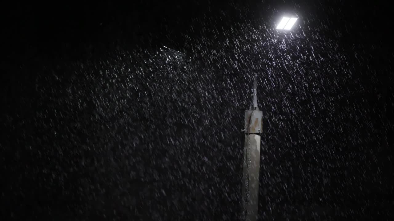 夜间大雨下的双led灯柱。中等尺寸的雨滴对着灯柱明亮的灯光。视频素材