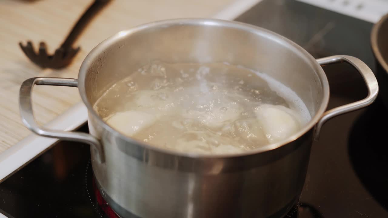 水在不锈钢炖锅里烧开。饺子是在厨房里煮的。视频素材