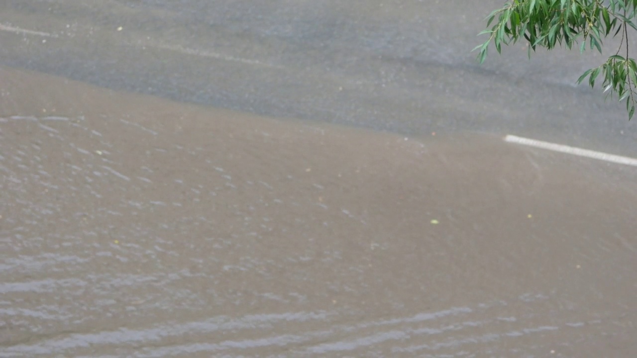 夏天汽车经过的城市街道被雨水淹没。大雨期间路上洪水泛滥。自然灾害泛滥在街道上视频素材