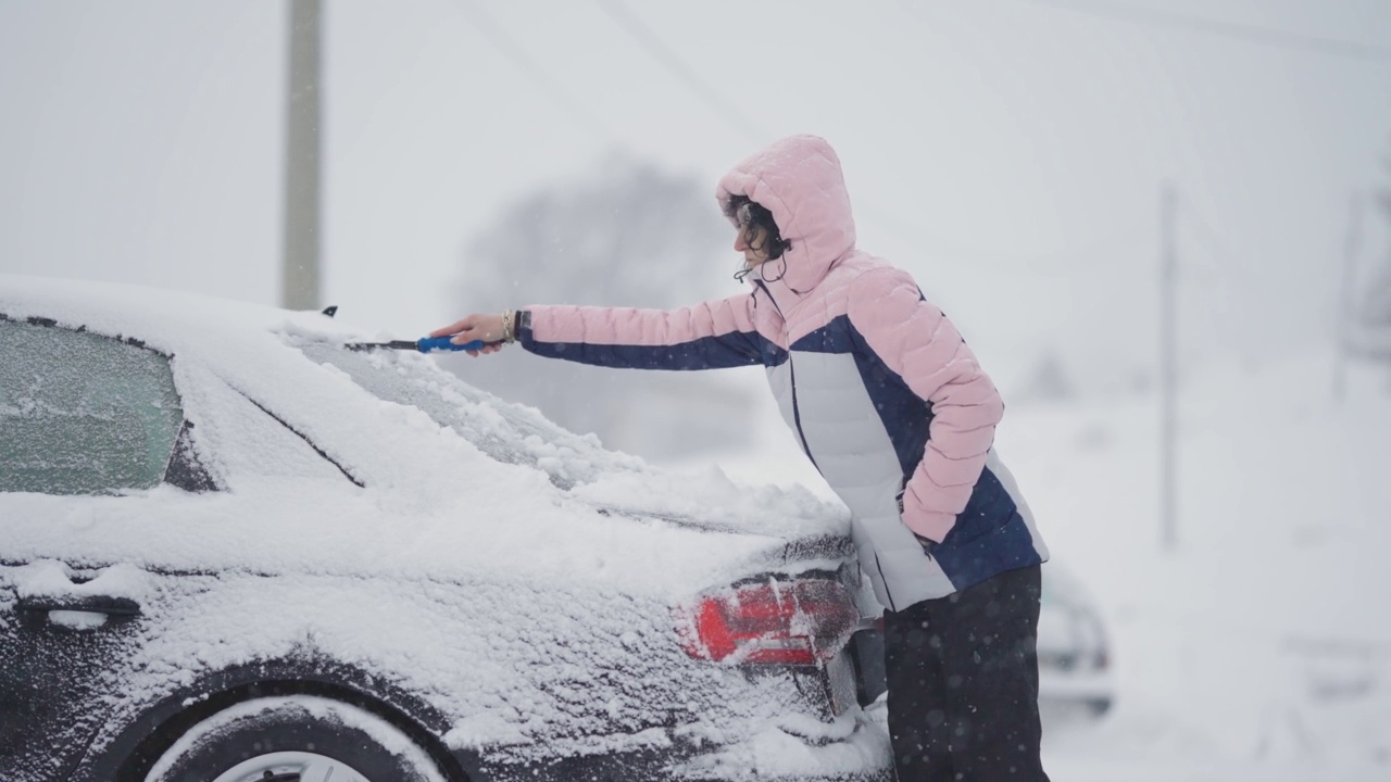 可爱的金发女人扫雪后从汽车视频素材