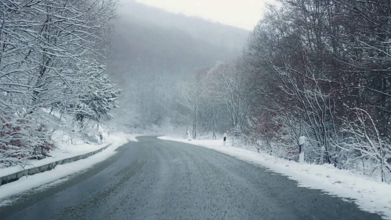 冬天的Pov开车在山滑结冰的道路上，松树和积雪覆盖的树枝视频素材