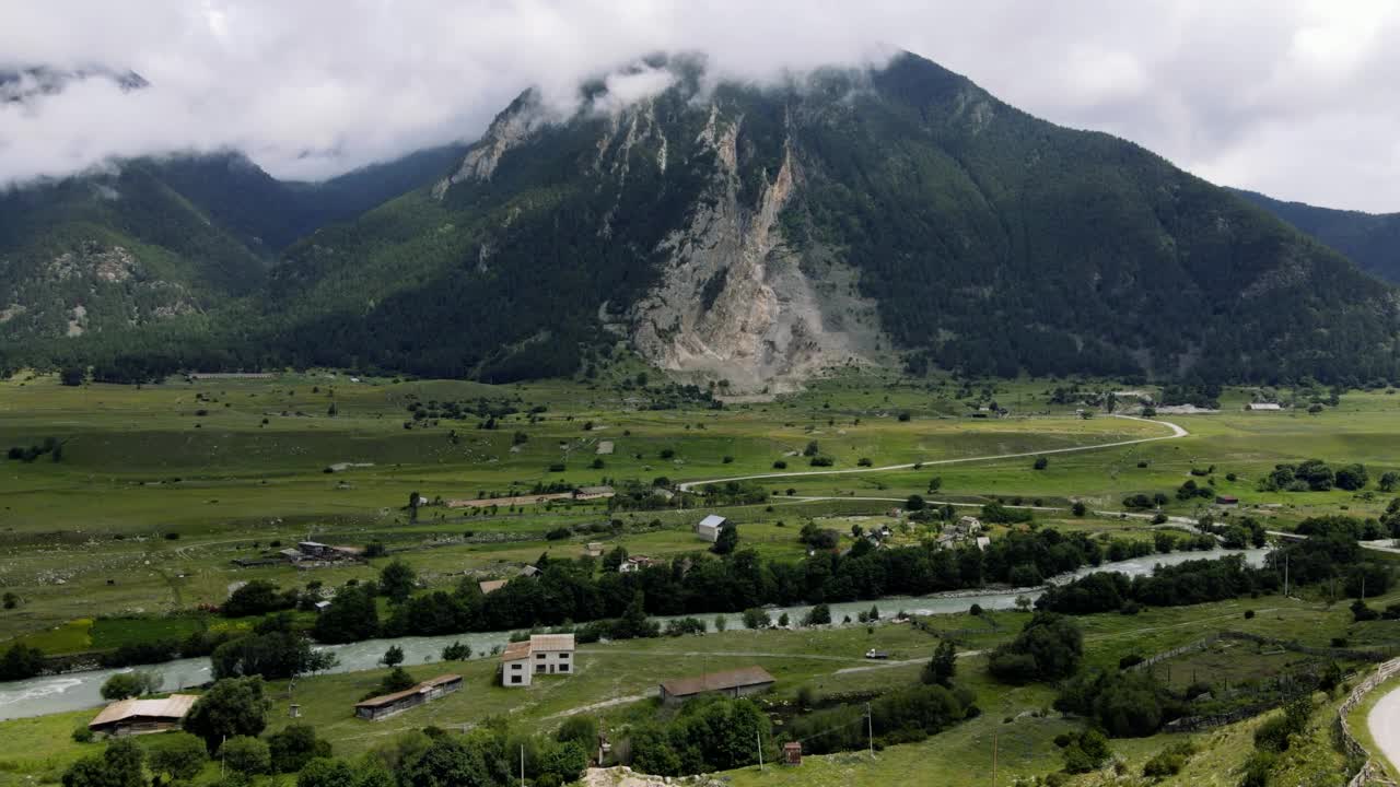 夏天，无人机在山上的一个小村庄和一条河流上空起飞。无人机的观点。视频素材