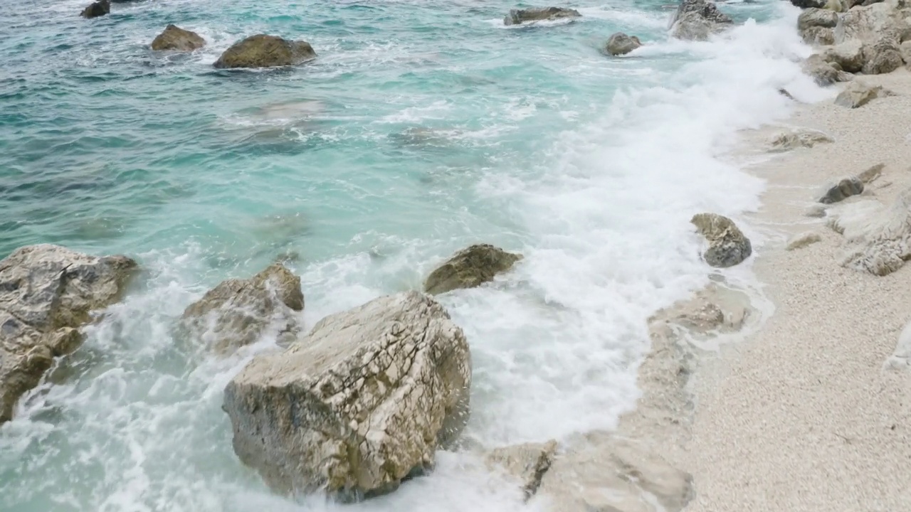 飞越岩石海岸，清澈的蓝绿色海水鸟瞰图夏季海景视频素材