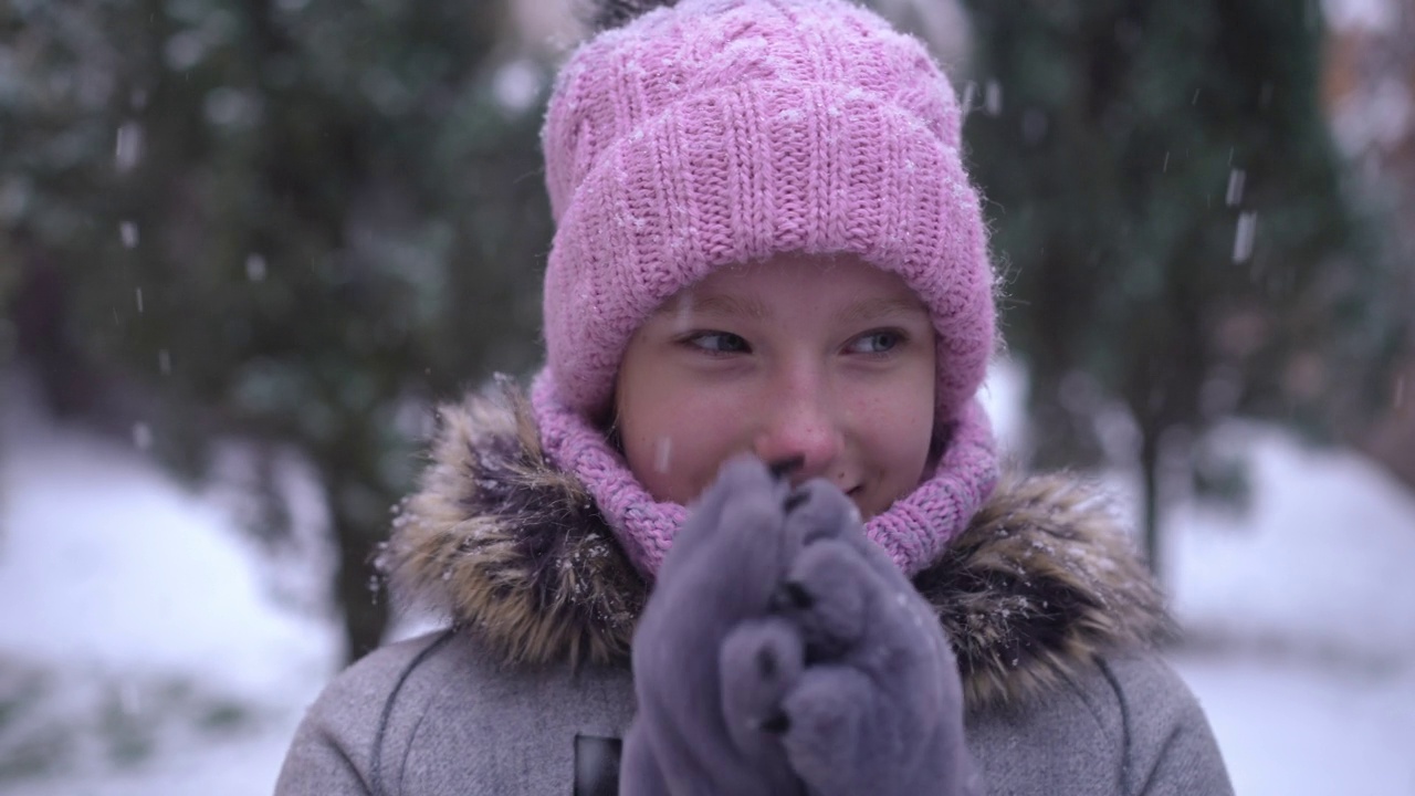 头像满意的青年白人女孩温暖的手搓手掌在慢动作站在雪天户外。快乐的少年享受着冬天的闲暇，微笑着看向别处。视频素材