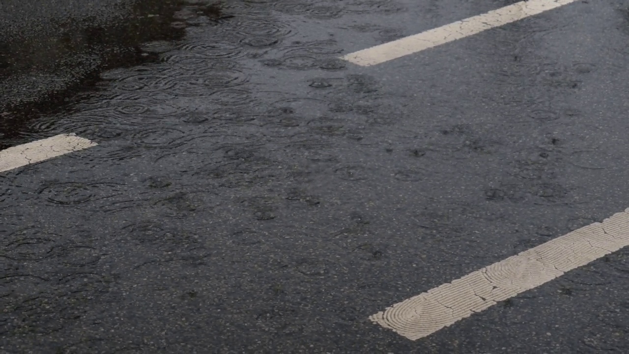 雨落在柏油路上。路上大雨滂沱。有地面标记的道路视频素材