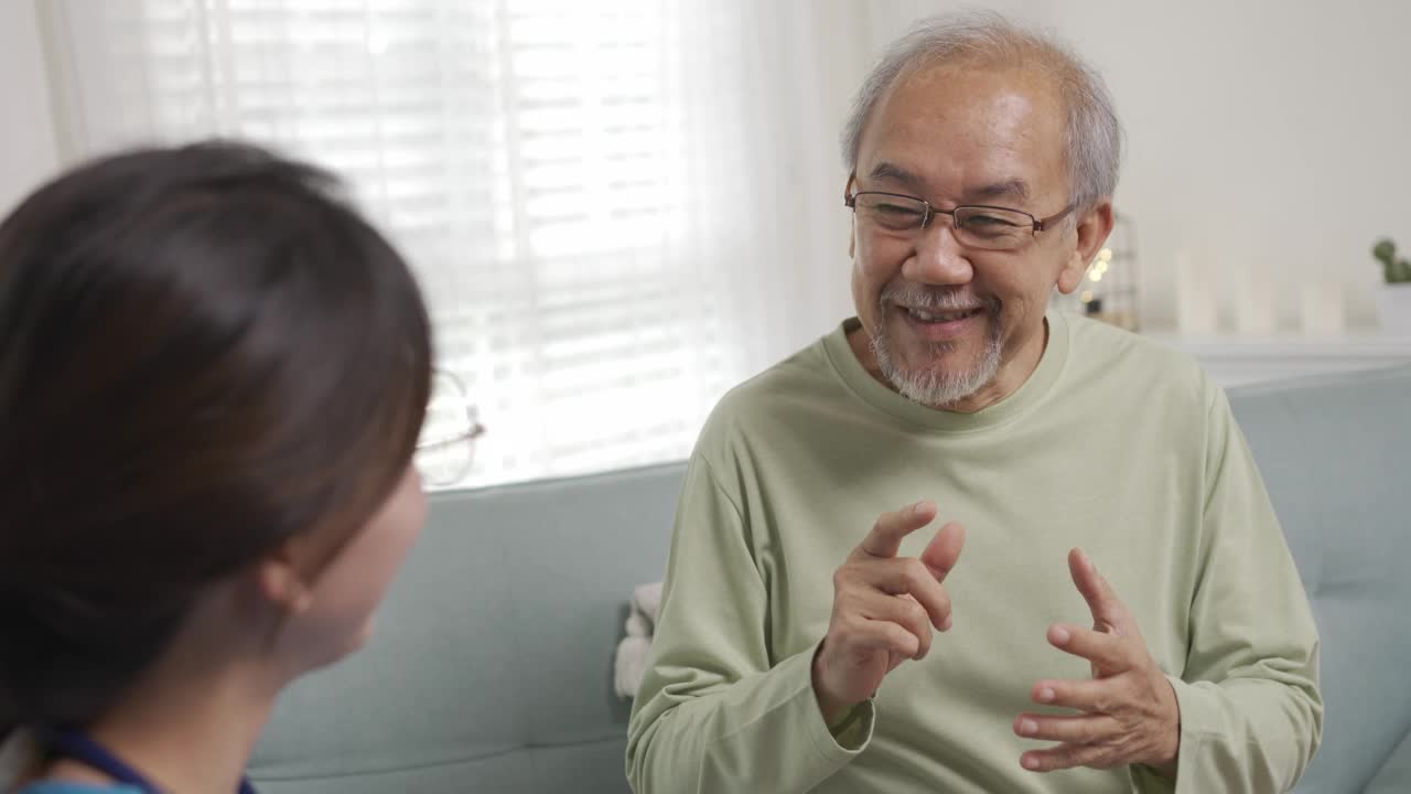 亚洲护理人员在家中客厅与年长男性病人交谈。年长的老人在理疗后咨询。护士辅助救援的概念。视频素材