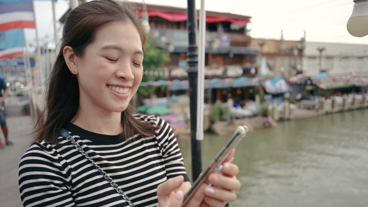 年轻的女网红拿着相机分享录制的视频。泰国安帕瓦的旅行剪辑和视频博主视频素材