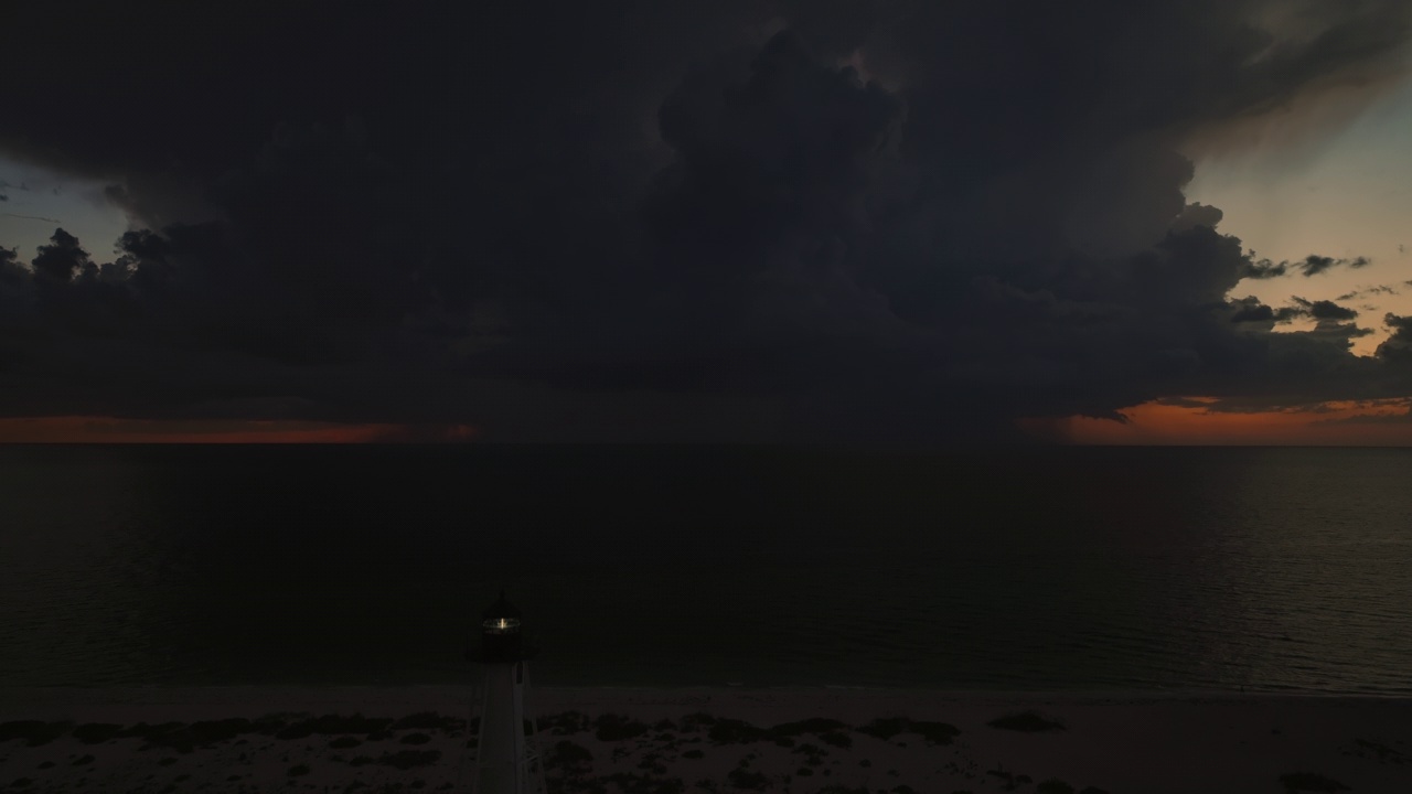 海岸上的白色灯塔，在暴风雨的夜晚闪烁着灯光，供商业船只航行。海面上有雷暴和闪电，对船只构成危险视频素材