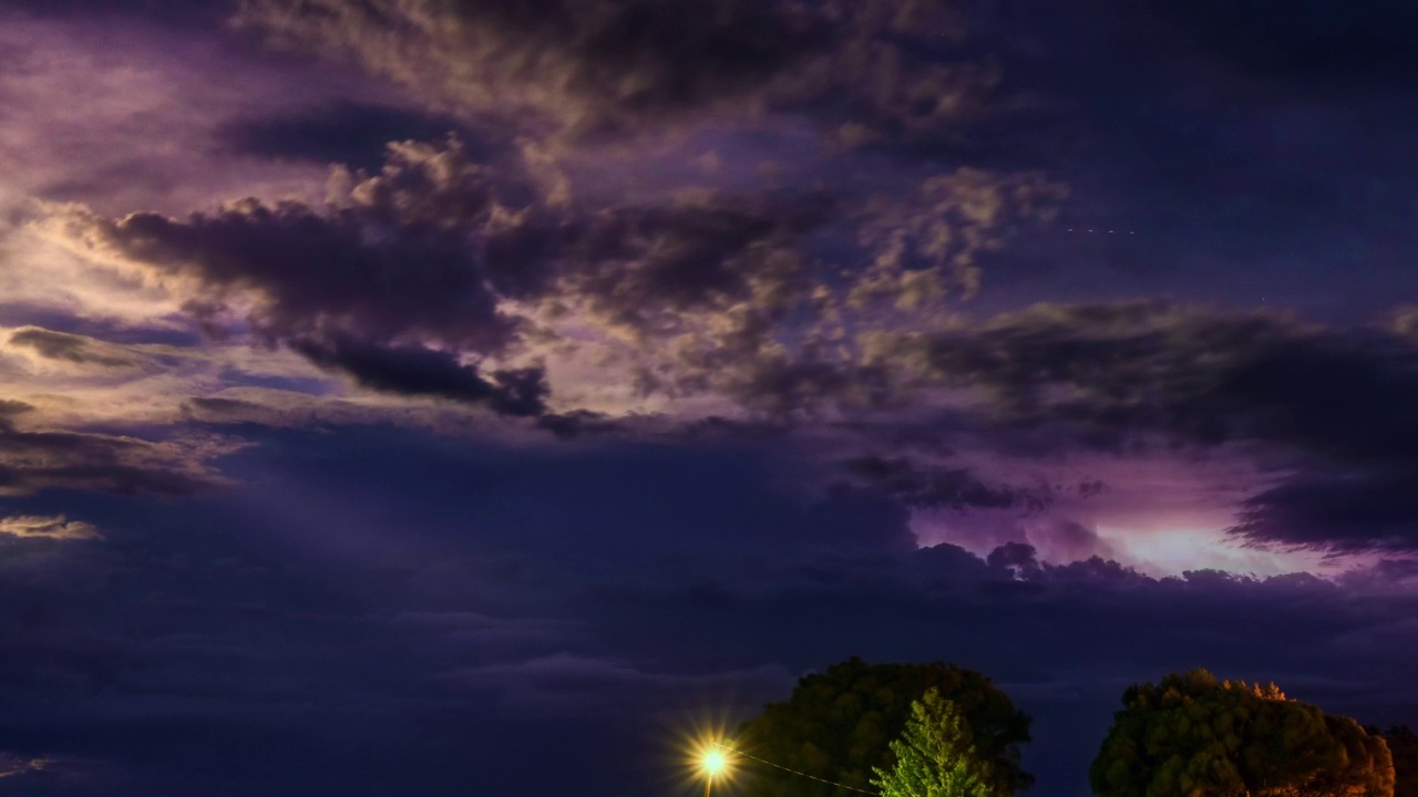 美丽的充满活力的紫色夜空在农村地区。在暴风雨的天空中可见的一连串闪电。时间流逝视频素材